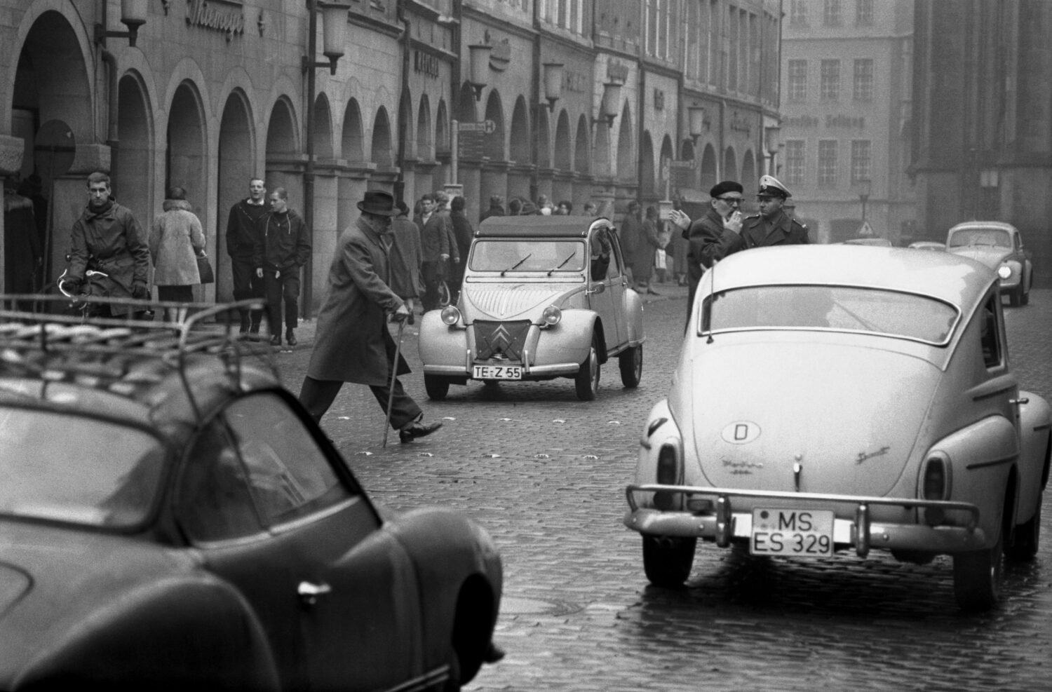 Prinzipalmarkt 1962: Viele Autos, ein hastender Fußgänger und ein Schutzpolizist
